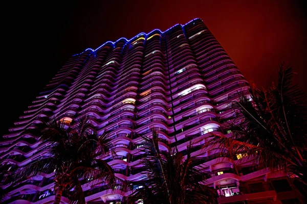 Arranha-céus altos e belas palmas, cidade noturna nos trópicos, a combinação de natureza e arquitetura . — Fotografia de Stock