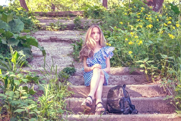 Όμορφη κοπέλα που κάθεται στις σκάλες στο πάρκο με λουλούδι, — Φωτογραφία Αρχείου