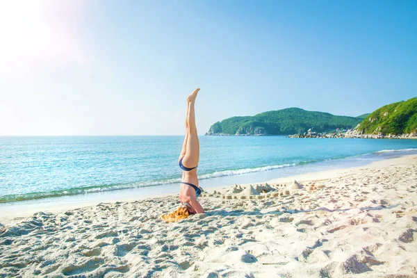 Jeune, belle, rousse fille pratique le yoga sur la plage . — Photo