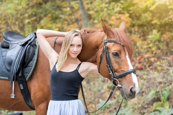 Une jeune fille blonde posant avec un cheval, une belle fille et un cheval fort . — Photo