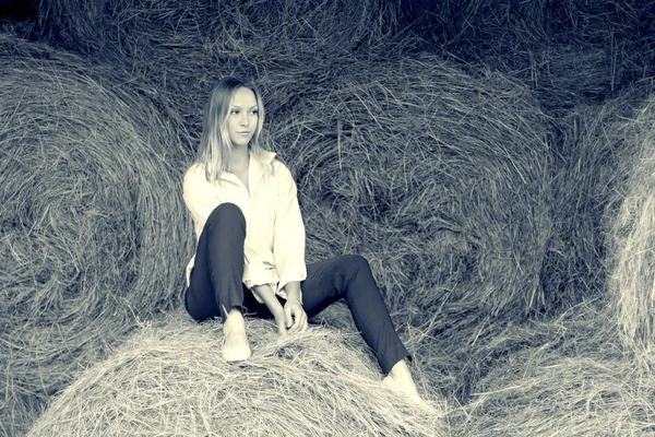 Krásná mladá dívka s košili a kalhoty sedí ve stodole. — Stock fotografie