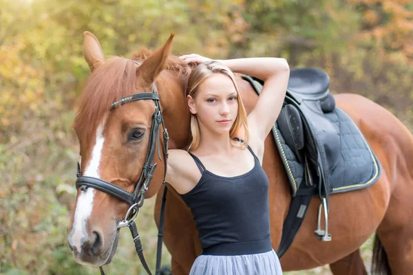 Une jeune fille blonde posant avec un cheval, une belle fille et un cheval fort . — Photo