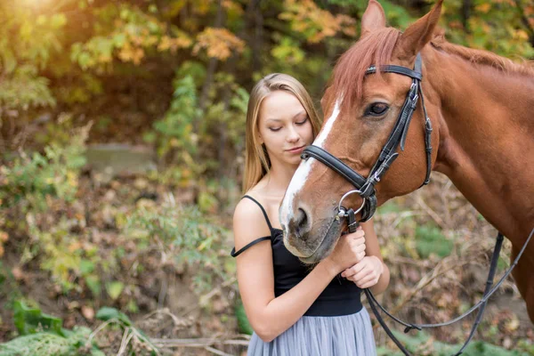 En ung, blond tjej som poserar med en häst, en vacker flicka och en stark häst. — Stockfoto