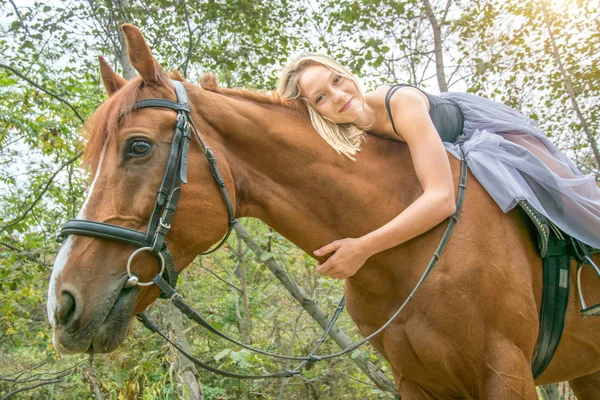 En ung, blond tjej som poserar med en häst, en vacker flicka och en stark häst. — Stockfoto