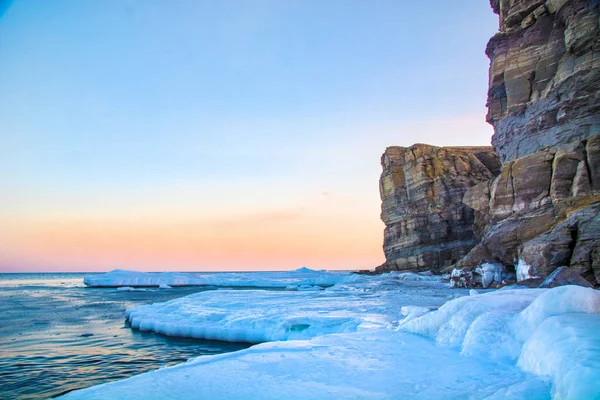 Wysokie klify nad morzem, wszystko w lodzie. Crag o zachodzie słońca w lodzie. piękny krajobraz z wychodzących słońce. — Zdjęcie stockowe