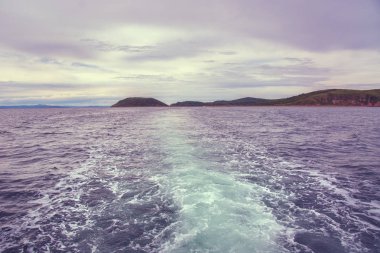 arkasından su ve kabarcıklar güzel bir tüy tekne yüzen ufukta adanın görebilirsiniz. 