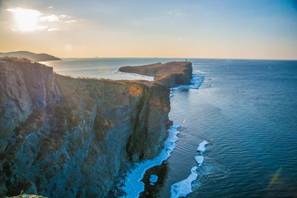 Altos penhascos no mar, todos em gelo. Crag ao pôr-do-sol no gelo. uma bela paisagem do sol extrovertido . — Fotografia de Stock