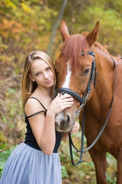 A young, blonde girl posing with a horse, a beautiful girl and a strong horse. — Stock Photo, Image