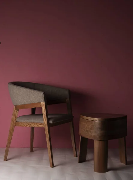 Şilla de madera de lujo con mesa de madera pulida con tres patas en un espacio con conted rosada y piso en colores crema con luz de la maana