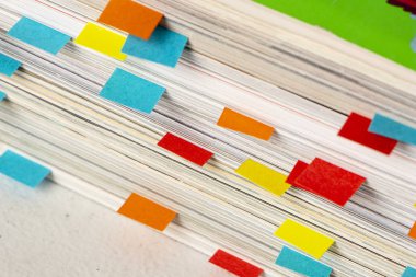 Birinci plano de pila de revistas con etiquetas de colores como marcadores de paginas hekhos con papelhoes pequeos de colores