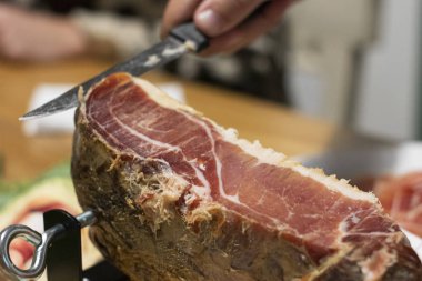 Mano de Hombre cortando jamn curado con cuchillo con tajada muy delgada en casa con luz clida en la noche