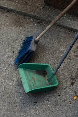 Escoba azul con regedor de basura verde en la calle de cemento quietas sin moverse. Quietud de la ciudad en cuarentena
