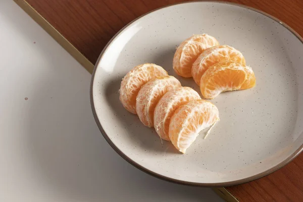Cascos de Mandarina en plato bej rengi. Comida durante pandemia. Alimentacin kullanışlı de frutas
