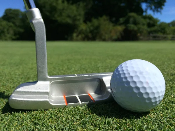 Мяч для гольфа и клюшка на зеленом поле — стоковое фото
