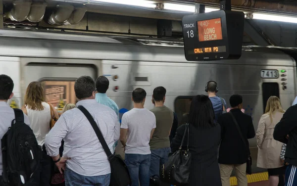 Le train LIRR quitte le terminal de Penn Station. Les gens attendent l'embranchement Long Island Railroad Long Beach depuis Manhattan sur la plate-forme de la voie ferrée — Photo