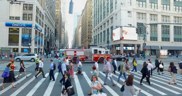 FDNY camión de bomberos cruzando concurrida intersección Manhattan durante la hora punta de la mañana. Gente de viaje a pie al trabajo en Midtown — Foto de Stock