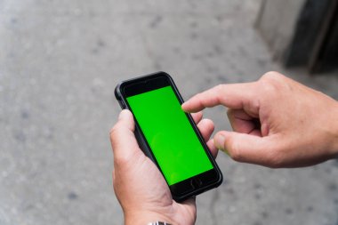 Akıllı cep telefonu ile yeşil perde grafik kaplaması için tutan adam. Parmak dokunmatik tuşlar uygulaması ile etkileşim