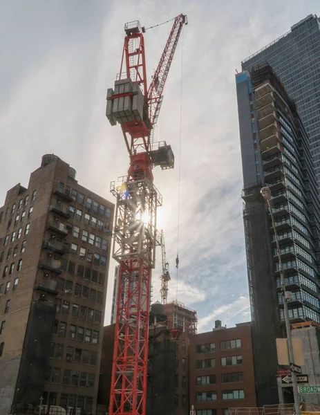 Manhattan construction crane stand tall in NYC skyline building new tall skyscraper. Sun shine through support evening background