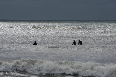 Siluet yakalamak ve büyük binmek sörfçü panoları okyanusta bekliyor binmek beach kıyıya dalgalar.