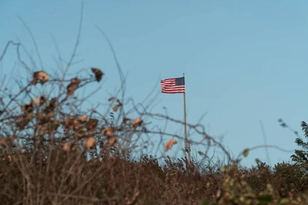 美国国旗在白天的风中飘扬在绿色空间国家公园上空, 以晴朗的蓝天为背景。自由的奥萨象征 — 图库照片