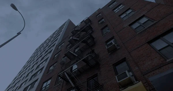 Photo extérieure Immeuble de style NYC au-dessus des stores avant du magasin la nuit. Vue verticale vers les fenêtres et sortie de secours sur la façade — Photo