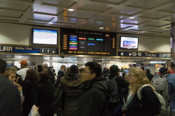 Les passagers du Long Island Railroad attendent dans le hall sous un grand panneau pour les annonces de voie ferrée quittant New York pour rentrer chez eux pendant les heures de pointe — Photo