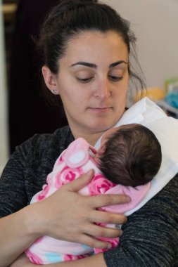 Güzel yeni anne omzunda geğirmek için biberon la beslendikten sonra kollarında onu yeni doğan bebek kız tutar