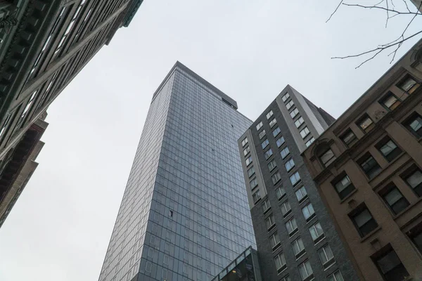 ニューヨーク スタイルの超高層ビルのオフィスビル ストリート レベルから下の小さいアパートの垂直方向のビューを検索します — ストック写真