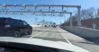 POV driving forward view passing highway cashless toll plaza sensors before crossing suspension bridge in New York City. clipart