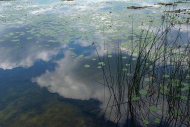 Bulutlar gölün berrak sularında yansıyor.