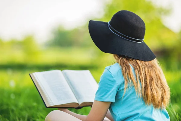 Kız bir çim üzerinde oturur ve bir kitap okur — Stok fotoğraf