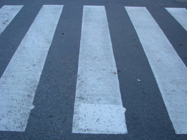 İnsanlar caddeden karşıya geçerken güvenlikleri için yaya geçidinde yürüyorlar..