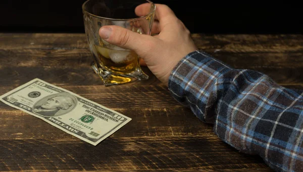 木製のテーブルの上にお金をウイスキーのグラス — ストック写真