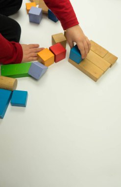 El, tahta bir küp yerleştirir. Beyaz bir arka planda izole edilmiştir. Çocuk ahşap kibiklerle oynuyor.