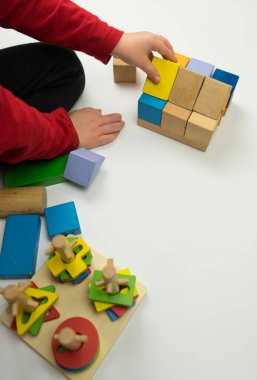 El, tahta bir küp yerleştirir. Beyaz bir arka planda izole edilmiştir. Çocuk ahşap kibiklerle oynuyor.