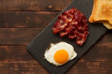 Kızarmış yumurta ve pastırma. Ev yapımı kahvaltı, ahşap arka planda ve tahta tahtada. Pastırmalı ve yumurtalı Sedwich..