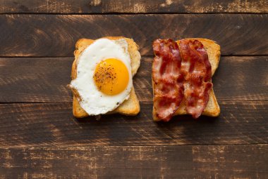 Kızarmış yumurta ve pastırma. Ev yapımı kahvaltı, ahşap arka planda ve tahta tahtada. Pastırmalı ve yumurtalı Sedwich..