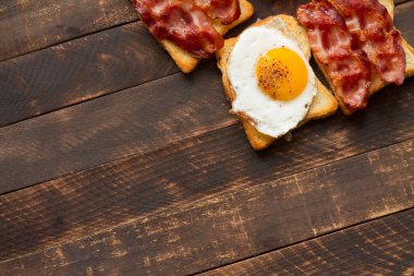 Kızarmış yumurta ve pastırma. Ev yapımı kahvaltı, ahşap arka planda ve tahta tahtada. Pastırmalı ve yumurtalı Sedwich..