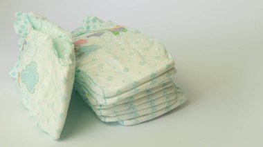 Beyaz arka planda yığılmış bebek bezi yığınları. Sağlık Hizmetleri