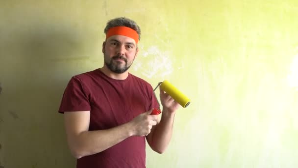 Bearded man against the wall. Good mood. In the hands of a construction roller for wallpaper. Repair work in the room. Frick. Retro style. Green wall. — Stock Footage Bearded Man Wall Good Mood Hands Construction Roller Wallpaper Repair Stock Video