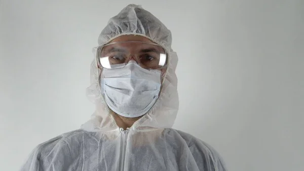 A man in protective clothing. On the face are glasses and a mask. Portrait of one man. The fight against the virus. Light background.