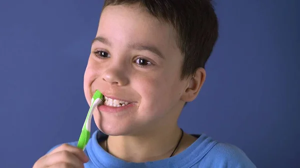 The boy is brushing his teeth. Age 6 years. Funny view. Funny look. Close-up portrait.