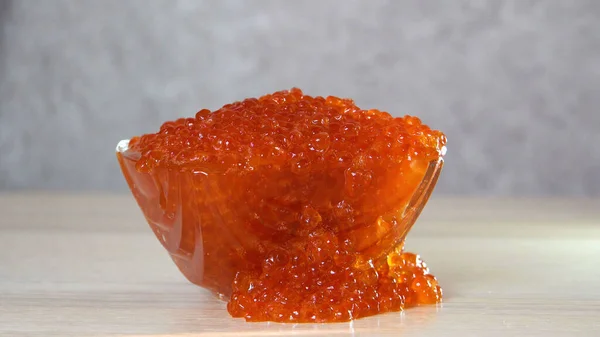 Red caviar in a glass vase. Edible product. Wooden table. Traditional food. Concept. Close-up.