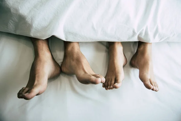 Barfodet af elskere under tæppe i soveværelset. Ferie og lykke af seksuel. Valentinsdag tema. Ferie morgen tema - Stock-foto