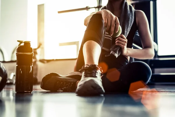 Sport kobieta siedzi i odpoczywa po treningu lub ćwiczeń w siłowni fitness z shake białka lub wody pitnej na podłodze. Spokojnie. Trening siłowy i ciało budować temat. Ciepły i chłodny ton — Zdjęcie stockowe