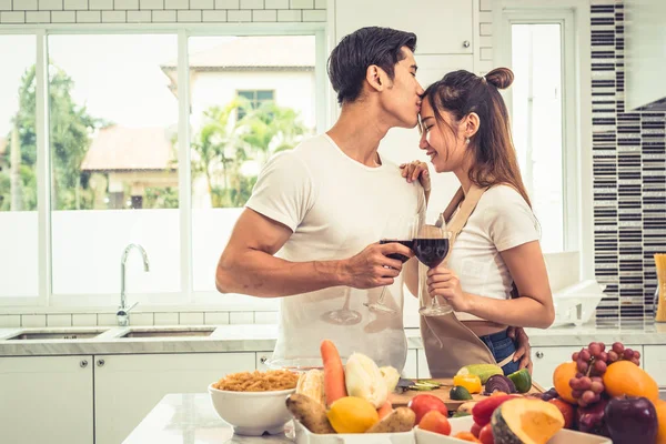 Aziatische liefhebbers of koppels kussen voorhoofd en het drinken van wijn op kamer van de keuken thuis. Liefde en geluk concept zoet wittebroodsweken en het thema van de dag van Valentijn — Stockfoto