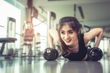 Asya genç kadının gönderme yapması ups ile Halter kattaki fitness spor salonu ve ekipmanları arka planda. Egzersiz ve spor egzersiz kavramı. Sağlıklı ve mutluluk kavramı. Güzellik ve vücut tema oluşturmak.