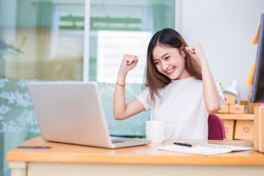 Asyalı kadın kendini ofiste dizüstü bilgisayarlar ve internet kullanırken zevk. İş ve pazarlama ve yarı zamanlı bir kavram. Line alışveriş ve iş başarı tema üzerinde. İş bittiğinde mutlu ruh hali.