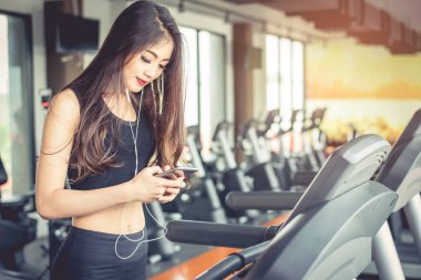 Asyalı kadın akıllı kullanarak telefon ne zaman koşu bandı üzerinde fitness salonunda egzersiz ya da gücü eğitim. Sakin ol ve teknoloji kavramı. Egzersiz ve sağlık Tema spor. Mutlu ve rahat ruh hali.