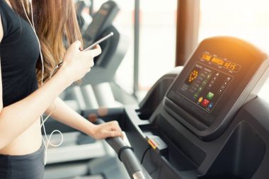 Asyalı kadın akıllı kullanarak telefon ne zaman koşu bandı üzerinde fitness salonunda egzersiz ya da gücü eğitim. Sakin ol ve teknoloji kavramı. Egzersiz ve sağlık Tema spor. Mutlu ve rahat ruh hali.